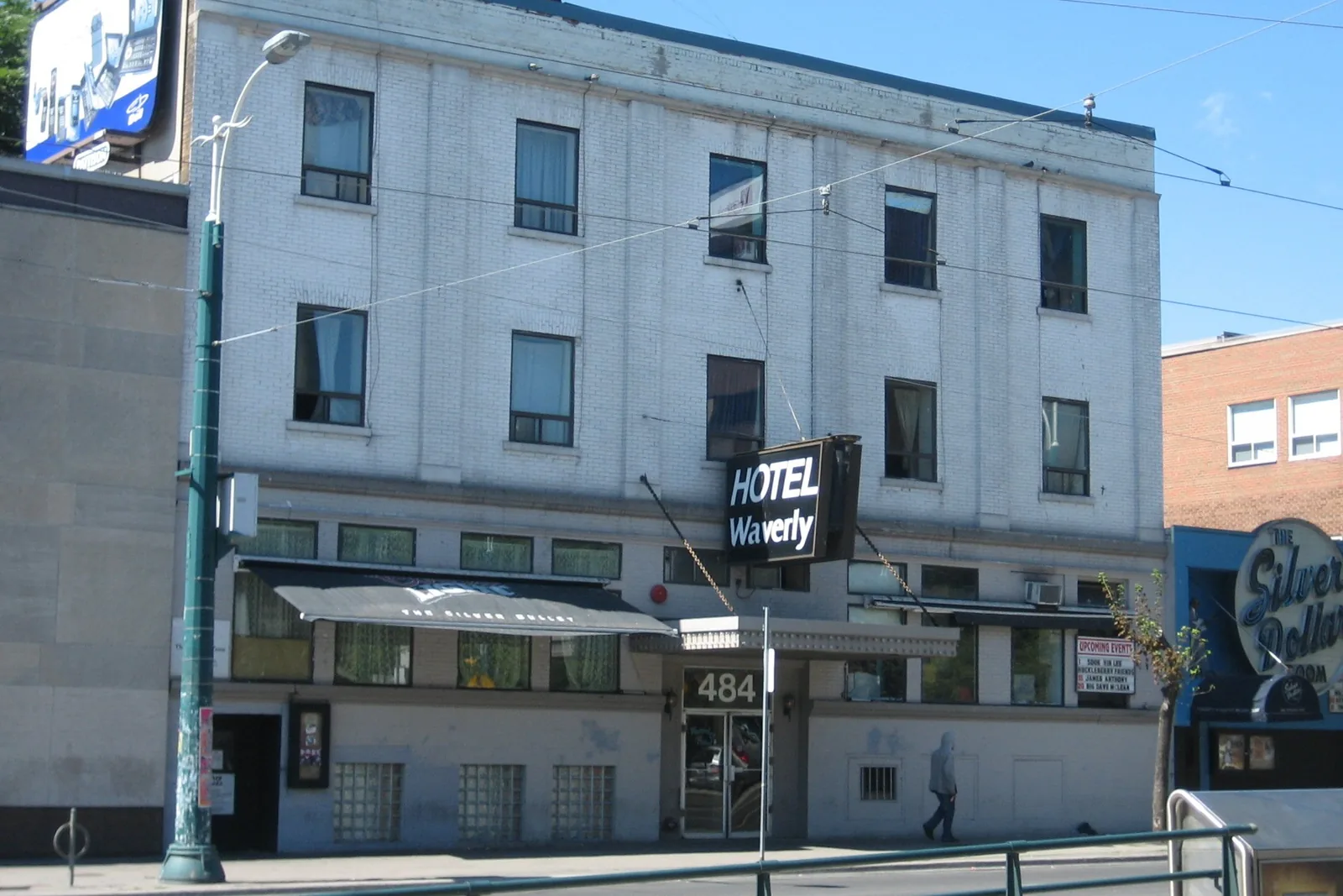The Hotel Waverly at 484 Spadina in daylight, white brick, the Silver Dollar awning and round sign at street level.