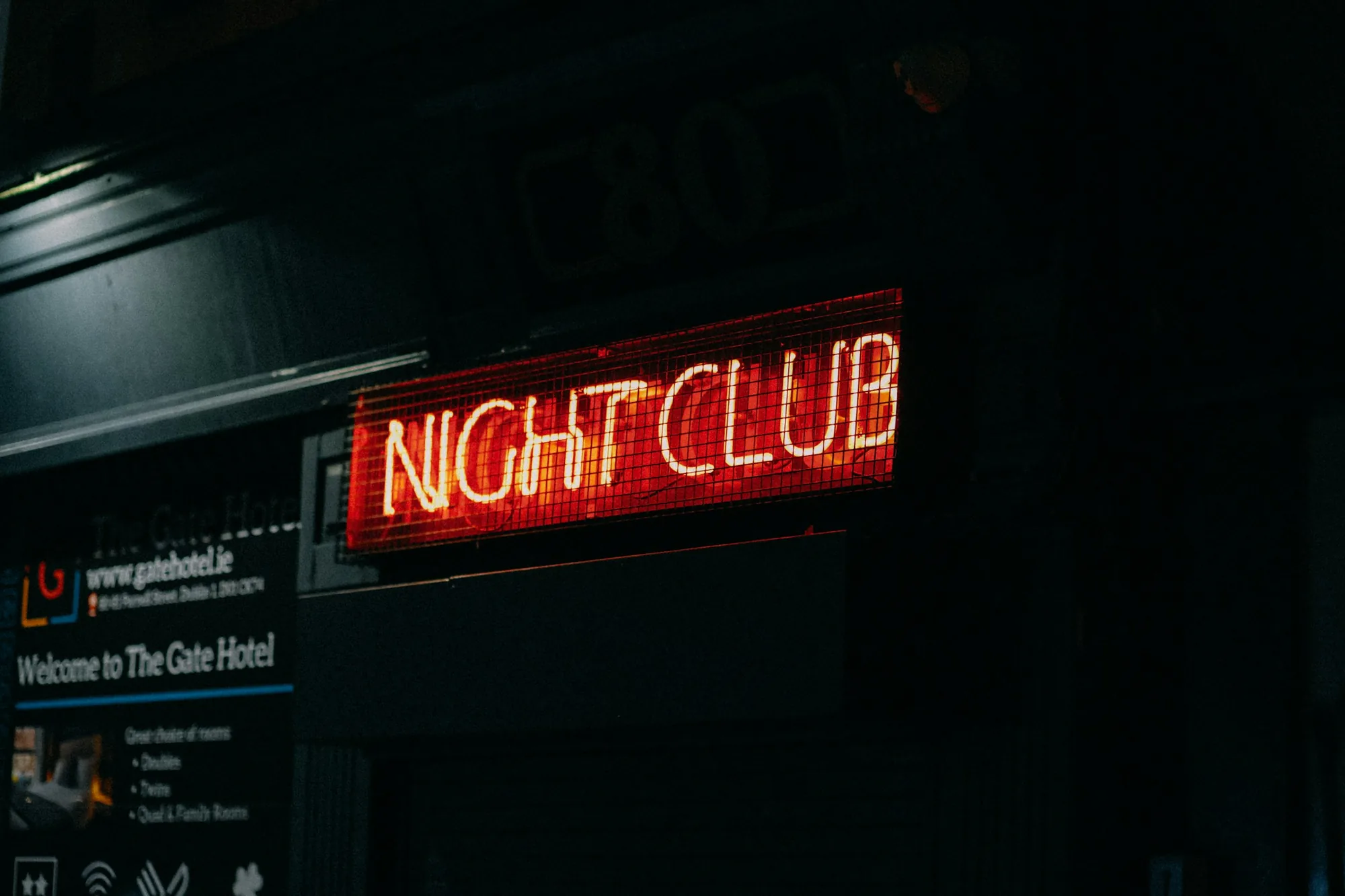 Red neon NIGHT CLUB sign on a city street at night.