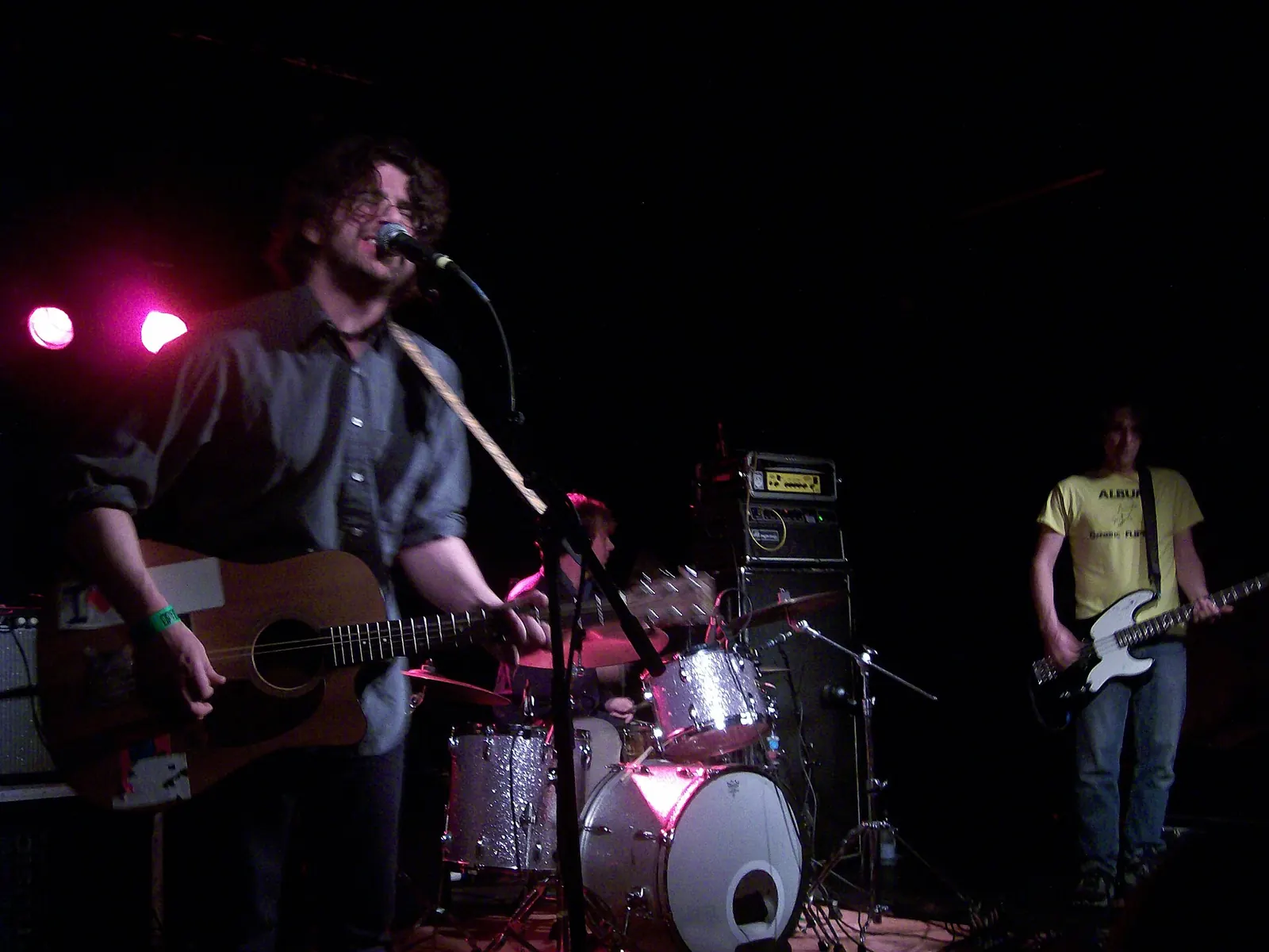 Sebadoh performing, a guitarist at a microphone under red stage light.