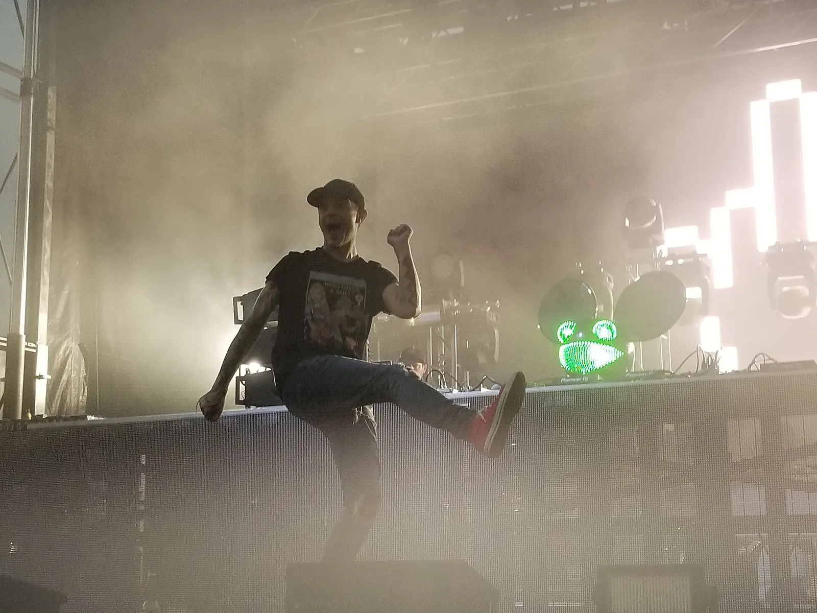deadmau5 performing live, mask on, one leg raised.