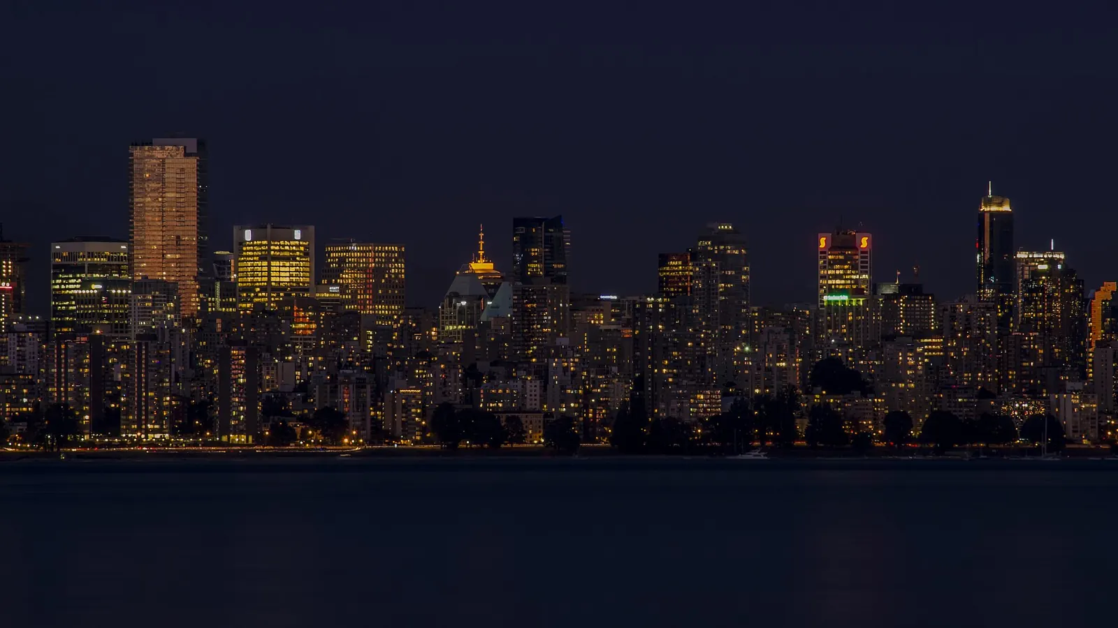 Vancouver skyline at night from Spanish Banks, towers across the water.