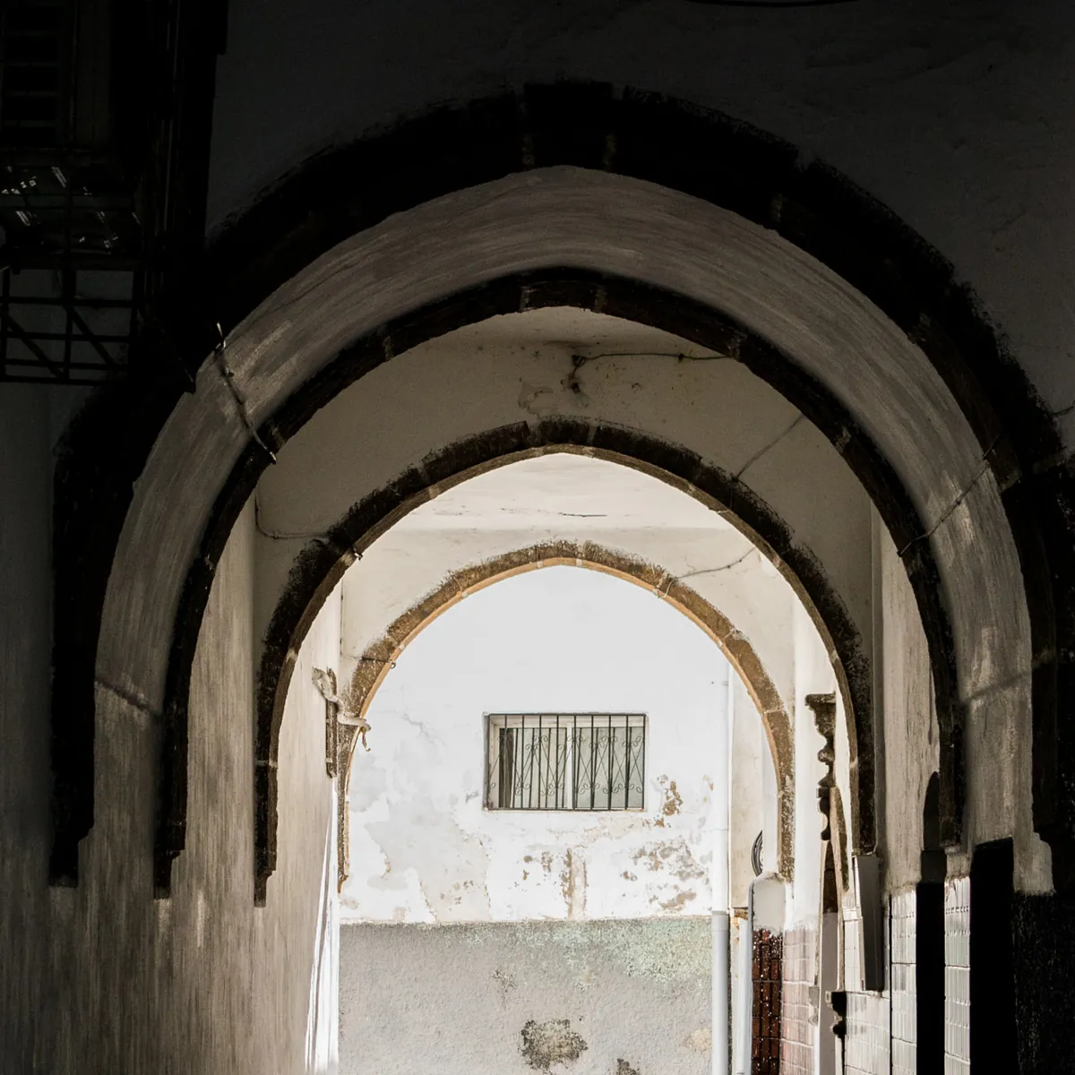 Dark brick arch tunnel, warm light at the far end, no people. Photo: Badr Outal, CC BY 3.0.